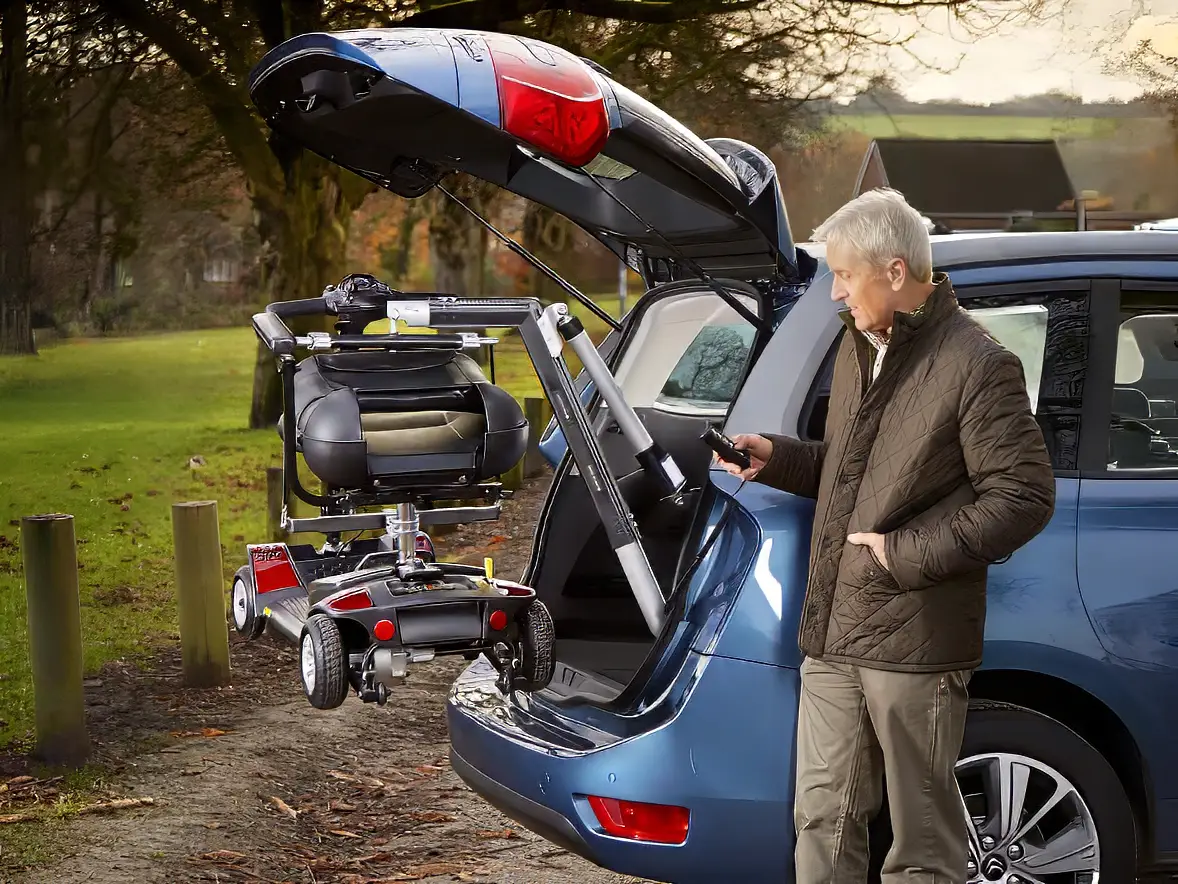 An elderly man loading his scooter into his van using a lift.